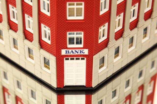 makieta budynku banku z czerwonej cegły, wraz z jego odbiciem lustrzanym